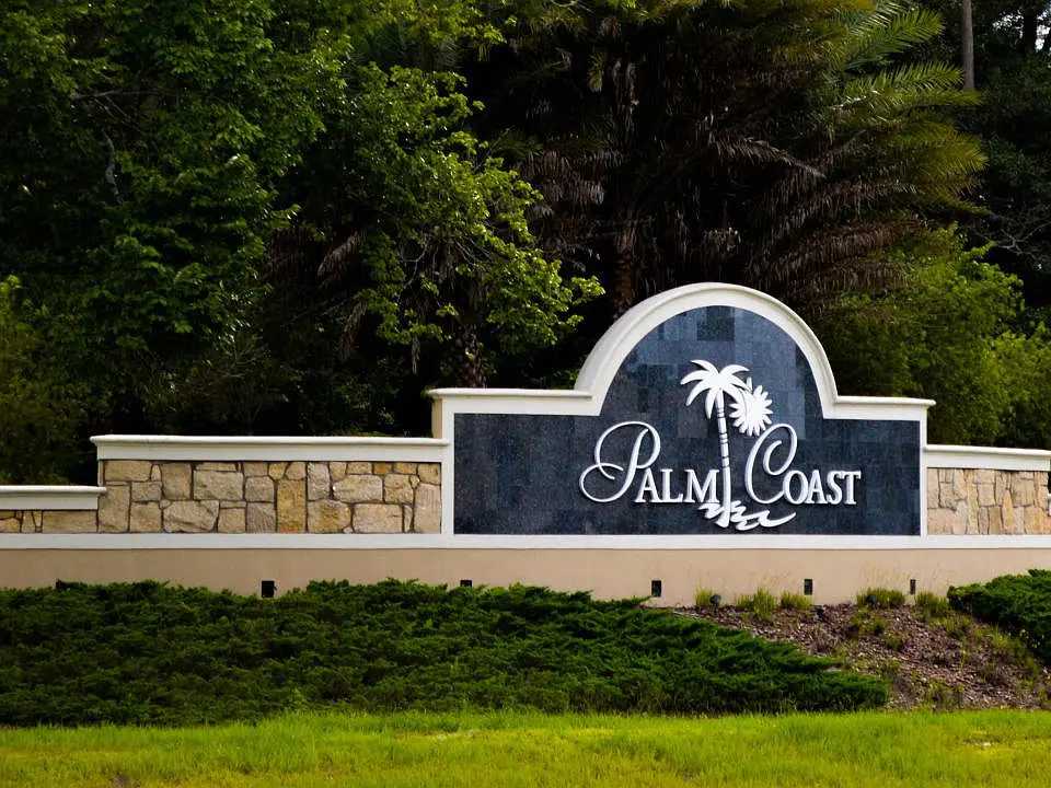 Palm Coast entrance monument framed by palm trees and Florida greenery in Palm Coast, Florida